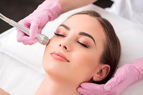 mujer tumbada recibiendo tratamiento facial